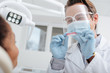 © LIGHTFIELD STUDIOS - selective focus of dentist in medical mask, face shield and latex gloves holding dental prosthesis near african american woman