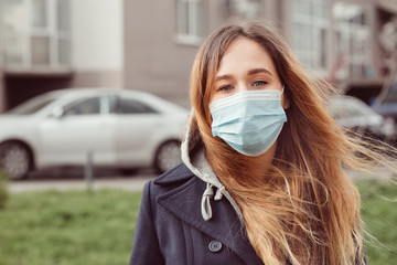 Closeup portrait of a girl in a medical mask on the street, epidemic of a coronavirus. The man violated the rules of self-isolation. SARS-CoV-2. protect yourself from COVID-19.