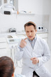 © LIGHTFIELD STUDIOS - selective focus of dentist pointing with finger at mouth and looking at african american patient