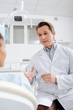 © LIGHTFIELD STUDIOS - selective focus of dentist looking at african american patient and gesturing in clinic