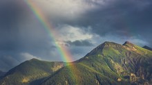 Scenic View Of Mountains Against Cloudy Sky With Rainbow