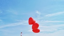 Low Angle View Of Heart Shaped Balloons Against Sky