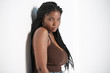 © Indico Studio/ADDICTIVE STOCK - Young African American female with braids leaning on white wall and looking at camera