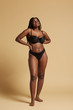© Indico Studio/ADDICTIVE STOCK - Curvy beautiful African American woman with braids in lingerie keeping hands on waist and looking at camera against yellow background