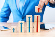 © Александр Кузьмин - The concept of growth, revenue or value increase. The cubes on the table of the businessman are arranged in ascending order, the cubes have arrows pointing up. The businessman sets the cube to the top
