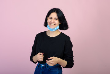 The caucasian girl in blue colored protective face mask. The girl looking at camera. Portrait shot over pink background. virus and pollution protection concept.