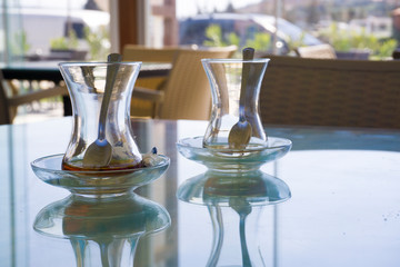 Two empty drunk Turkish tea glass on table in a cafe. Traditional famous Turkish drink as also known Cay or Demli Turk Cayi. Drinking tea to start a day positive or stay awake. Tea addiction concept.