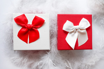 close up of a two white and red gift boxes , christmas, valentine's or birthday present , in white feathers, wedding decor