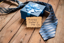 Happy Fathers Day Gift Box With Tie On A Rustic Wood Background.