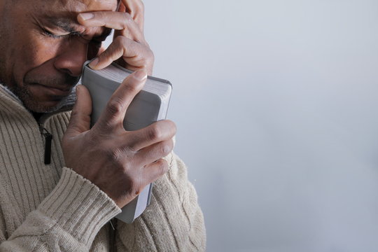 man praying to god with hands together Caribbean man praying with white background stock photo