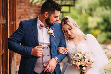Wall Mural - Portrait of a wedding couple of the bride and groom in a beautiful suit and dress, floral bouquet in an incredible place, horizontal photo