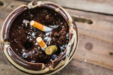 High Angle View Of Cigarette Butts And Cigar In Ashtray On Table