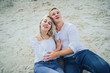 © Daria - Beautiful happy couple in love lying on a beach on sand in a white shirts are in love smiling. Summer, holidays, vacation and happy people concept