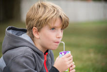 Portrait Of A Kid Drinking Juice With A Straw