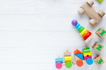 Wall Mural - Kids toys: pyramid, wooden blocks, xylophone, train on white wooden background. Top view. Flat lay. Copy space for text

