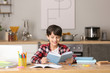 © Pixel-Shot - Little boy doing homework in kitchen