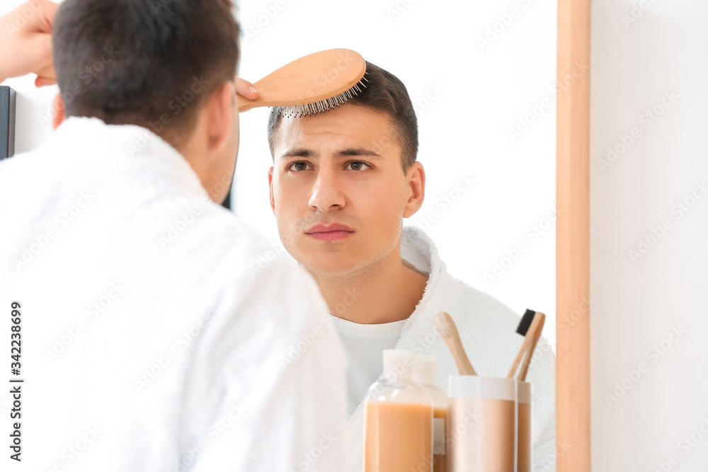 Handsome young man brushing hair at home