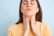 © Pixel-Shot - Young woman checking thyroid gland on color background