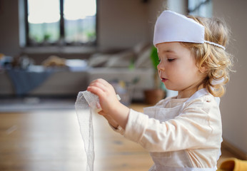 Wall Mural - Small toddler girl with doctor uniform indoors at home, playing.