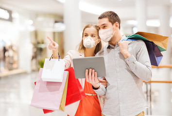 Sticker - sale, technology and pandemic concept - happy young couple with shopping bags and tablet pc computer wearing face protective medical mask for protection from virus disease in mall