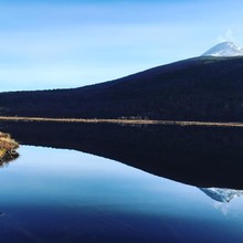 Scenic View Of Hill Reflecting On Lake Against Clear Blue Sky
