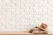 women's casual outfits and brown trendy hat on wooden table over white brick wall. Minimalistic concept of home decor. Template.