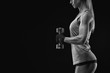 © USM Photography - Cropped black and white shot of a young woman lifting weights for body building training over black background. Muscular weightlifting woman.