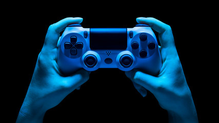 Hyman hands holding white video game gamepad in neon lights isolated on a black