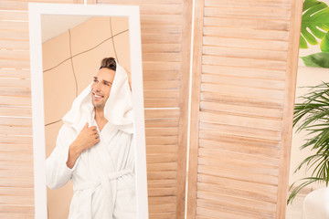 Wall Mural - Handsome young man wiping his hair near mirror