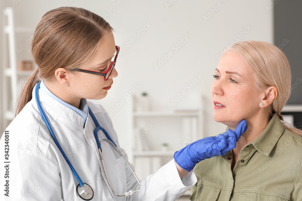 Doctor examining senior woman with thyroid gland problem in clinic