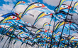 Colorful and bright bird flag kites on poles with a blue sky and clouds in the background at Southsea Kite Festival, Portsmouth, UK