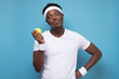 © Viktor Koldunov - Funny african american man holding green apple after sport training on blue wall