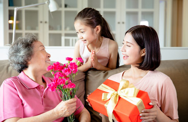 Happy mother's day  . Child and  mother congratulating grandmother  giving her flowers and  gift box