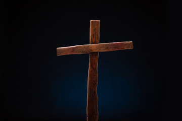 A wooden cross of Christ against a black background photographed in the studio