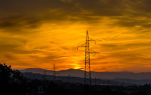 Low Angle View Of Silhouette Electricity Pylons Against Orange Sky During Sunset