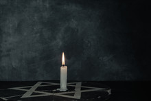 Close Up One Burning Candles And The Star Of David Against On A Dark Gray Background Wall.