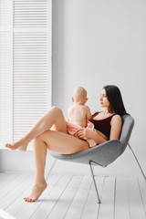 young mother with a baby sitting on a chair