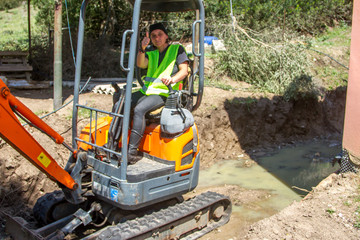 woman excavator going on a small excavator with yellow warning vest wearing  that makes the gesture of everything ok