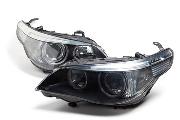 Wall Mural - Two xenon headlights for a German auto-optical equipment with a lens and corrector inside on a white isolated background in a photo studio. Spare part for the repair of the front body in the workshop.