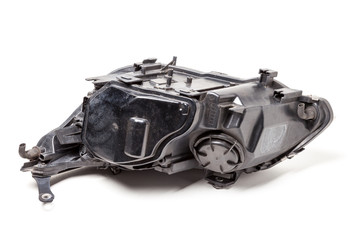 Plastic spare part of a black car on a white background - rear view xenon headlight with a closed lid inside electrical systems and optical equipment components of a lamp and reflectors with wires.