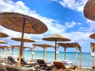 A group of lawn chairs and reed parasols from the sun sitting on top of a beach. High quality photo