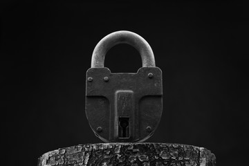 Large old padlock close - up on a black background. Black and white photo