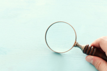 Wall Mural - vintage magnifying glass with wooden handle over blue background.