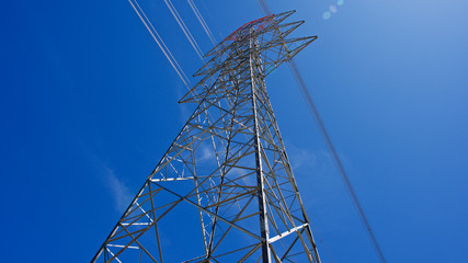 High voltage electrical tower. Electric poles in front of blue sky.