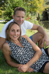 Poster - Romantic couple smiling and cuddling on lake side park in sunny day