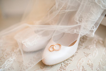 Gold Wedding Rings Lie On The Shoes Of The Bride Covered With A Veil
