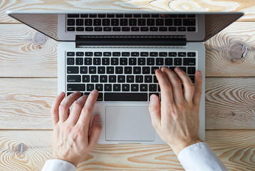 Poster - Top view of man's hands typing on laptop in sunny day. Coworking or working at home concept image.