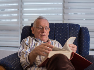 Wall Mural - Old man reading book at home