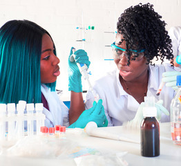 Wall Mural - Testing facility. Young African female scientists, medtech or medical students work together performing blood, nucleic acid and other medical tests for hospitals to diagnose patients with pneumonia.