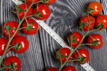 Wall Mural - Bunches of tomatoes. Near the measuring tape. On brushed pine boards. Symbol of World No Diet Day.